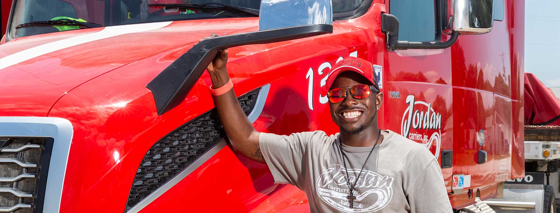 Guy standing beside a red truck with sunglasses on